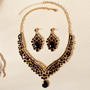 Dettaglio di un set di gioielli vintage in lega dorata con eleganti strass neri