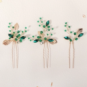Three-piece vintage gold hairpins with green crystals and leaf design on beige base