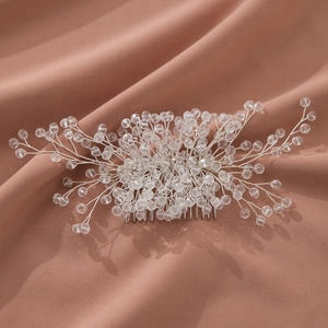 Elegant bridal hair comb with crystal beads and silver wire on pink fabric background