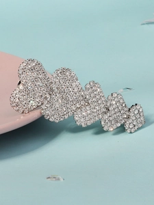 Detail of five linked heart hair clips with sparkling rhinestones on blue background