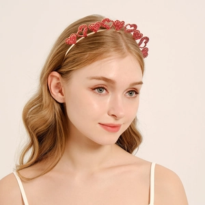 Detail view of a gold-tone headband with seven sparkling red rhinestone heart accents