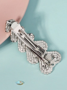 Close-up of silver-tone rhinestone hair clip with wavy crystal pattern on blue background