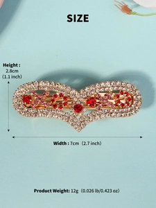 Detail view of a heart-shaped gold hair clip with red and pink rhinestones, 7cm width