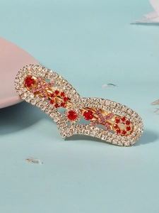 Detail of gold hair clip featuring red and pink rhinestones on light blue texture