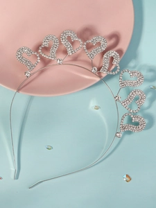 Detail of silver metal headband featuring sparkling rhinestone hearts on light blue background