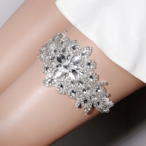 Macro view of handmade bridal garter featuring luxury rhinestones and pearl flower pattern