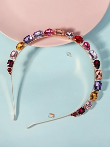 Détail d'un serre-tête en métal doré orné de strass colorés de diverses formes de coupe
