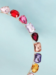 Vue détaillée de strass colorés en forme de poire sur un serre-tête doré fin