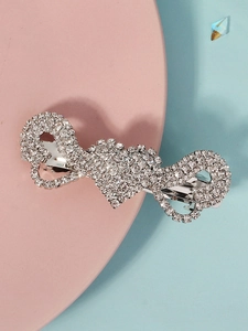 Detail of silver heart spring hair clip with sparkling rhinestones on a pink platform