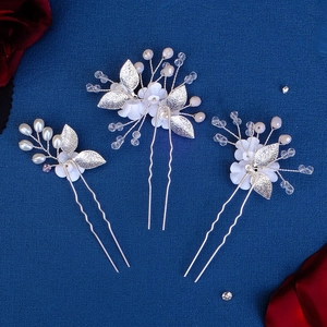 Detail view of handmade bridal hair pins with white clay flowers and pearls on blue fabric