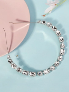 Détail d'un serre-tête argenté avec cristaux de formes variées sur fond pastel
