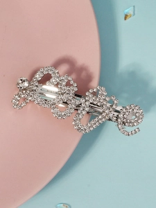 Close-up of sparkling silver rhinestone hair clip with intricate scrolled patterns