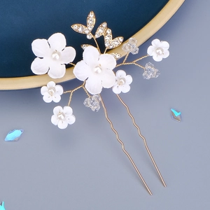Épingle à cheveux fleurs blanches avec perles et feuille dorée sur plat bleu