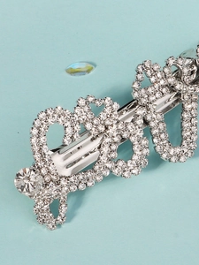 Detailed close-up of sparkling rhinestone pavé spring hair clip with wavy silver metal design