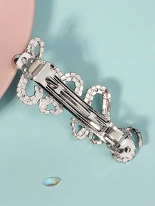 Detailed macro view of a silver hair clip with sparkling white rhinestones and ornate patterns