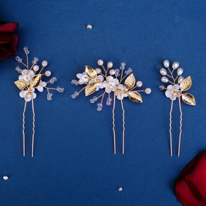 Detail of three gold floral hair pins with white petals and pearls for bridal styling