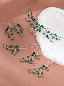 Détail macro du peigne à cheveux et boucles d'oreilles de mariée en cristal vert émeraude