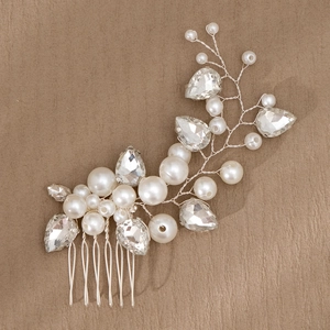 Detail of silver bridal hair comb with pearls and teardrop crystals on wood surface