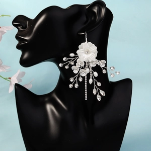 Dettaglio orecchini da sposa con fiori bianchi e perle su supporto per modelli