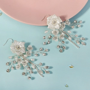Set orecchini sposa con fiori bianchi, perle e strass su sfondo colorato di alta qualità