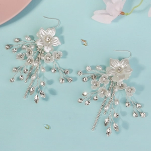 Dettaglio di orecchini a fiore con perle e strass brillanti con lunghe nappe a catena