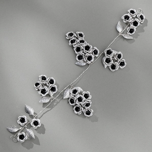 Close-up of handmade bridal headband with white flowers and black beaded metal leaves