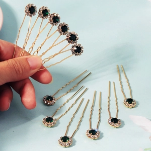 Vue macro d'épingles à cheveux dorées avec pierres vert émeraude et strass brillants