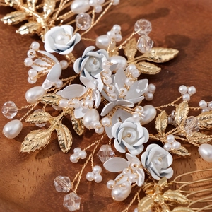 Elegant floral wedding hair comb with white petals, pearls and golden leaves on wood