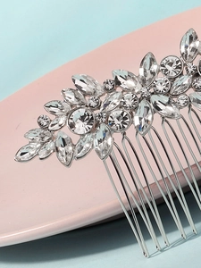 Macro shot of silver wedding hair comb with white crystals and leaf-shaped rhinestones
