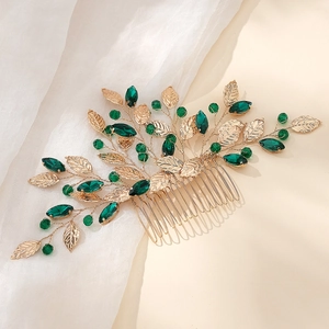 Detail of bridal hair comb with golden leaves and deep green crystals on soft tulle