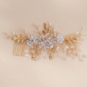 Close-up of handmade bridal hair combs with gold leaves, white flowers and pearls