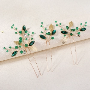Detail of three-piece bridal hair pins with gold leaves and emerald crystal accents