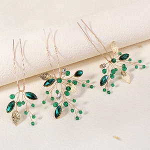 Elegant gold bridal hair pins set with emerald green crystals and leaf charms