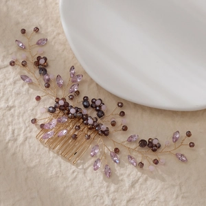 Detail of handcrafted gold hair comb with purple crystals and elegant beaded vine patterns