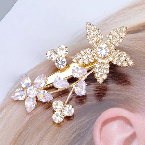 Détail d'une pince à cheveux de mariée dorée avec fleurs en zircons blancs et violets