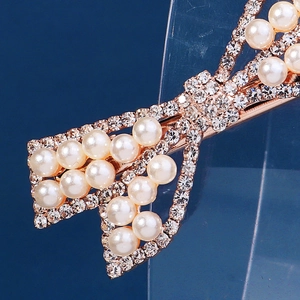 Elegant rose gold bow hair clip with pearls and rhinestones on a blue background