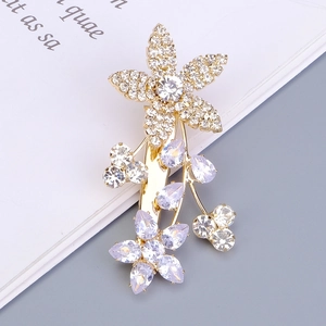 Détail d'une pince à cheveux fleur dorée avec strass poire violets et zircons blancs