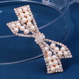 Detailed view of rhinestone bow hair clip with white pearls on rose gold metal