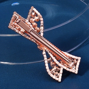 Detail shot of a rose gold rhinestone bow hair clip with luxury metal spring clasp