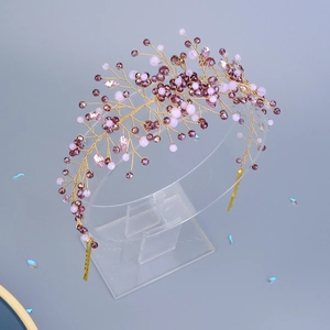 Detailed macro of handmade bridal headpiece with purple crystals and gold wire