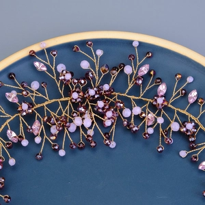 Close-up of handmade golden hair comb with purple crystals and rhinestones for bridal hairstyle