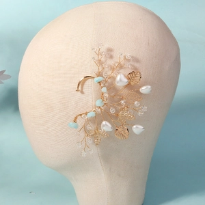 Detailed view of handmade gold wire ear cuff with white pearls and blue crystals