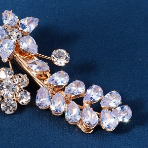 Barrette à cheveux fleurie plaquée or avec zircons cubiques sur fond bleu foncé