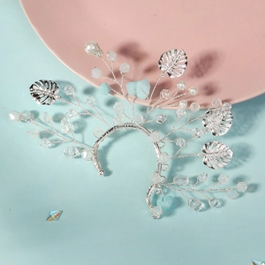Handmade crystal leaf ear cuff with pearls and blue stones on a light blue background