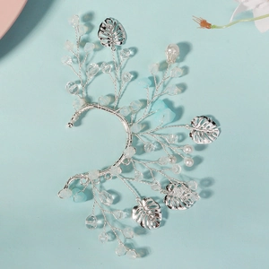 Detail of handmade crystal flower ear cuff with silver leaves and pearls on blue background