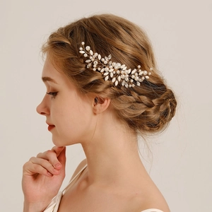 Détail du peigne à cheveux de mariée avec perles et feuilles dorées sur la mariée