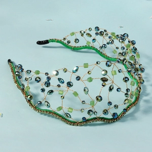 Detail of handmade green crystal headband with gold wire mesh and intricate beadwork texture