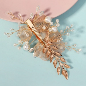 Elegant gold bridal hair clip with intricate metal flowers, pearls and crystals
