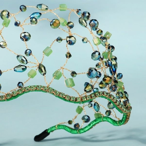 Detail of handmade gold wire headband with crystal beads and vintage green rhinestones