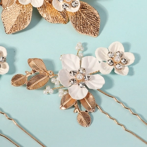 Peigne à cheveux de mariée doré avec fleurs blanches, feuilles et perles sur bleu